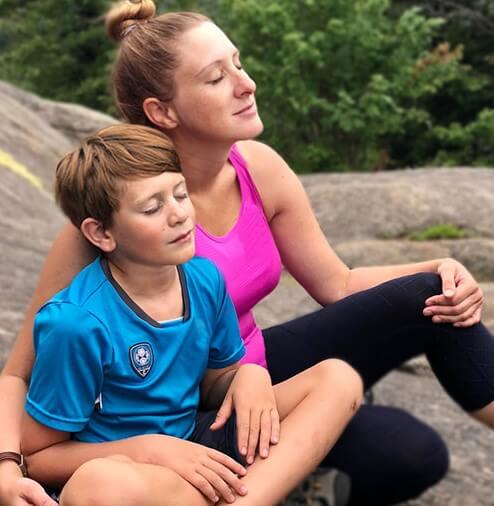 A mother and child sitting together in nature with their eyes closed