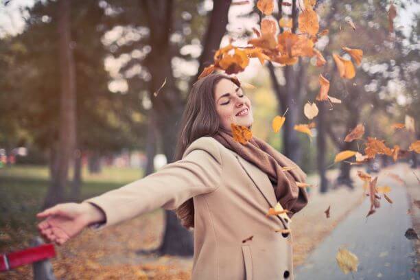 A woman throwing Autumn leaves on herself