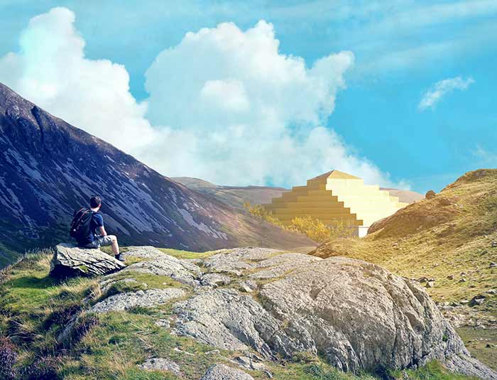 A man sitting on a rock looking at a temple placed among mountains