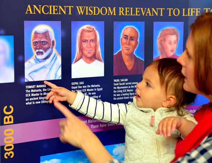 A mother and small child pointing at the spiritual teachers on an Eckankar display