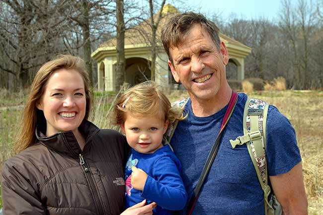 Two parents with their toddler smiling outdoors