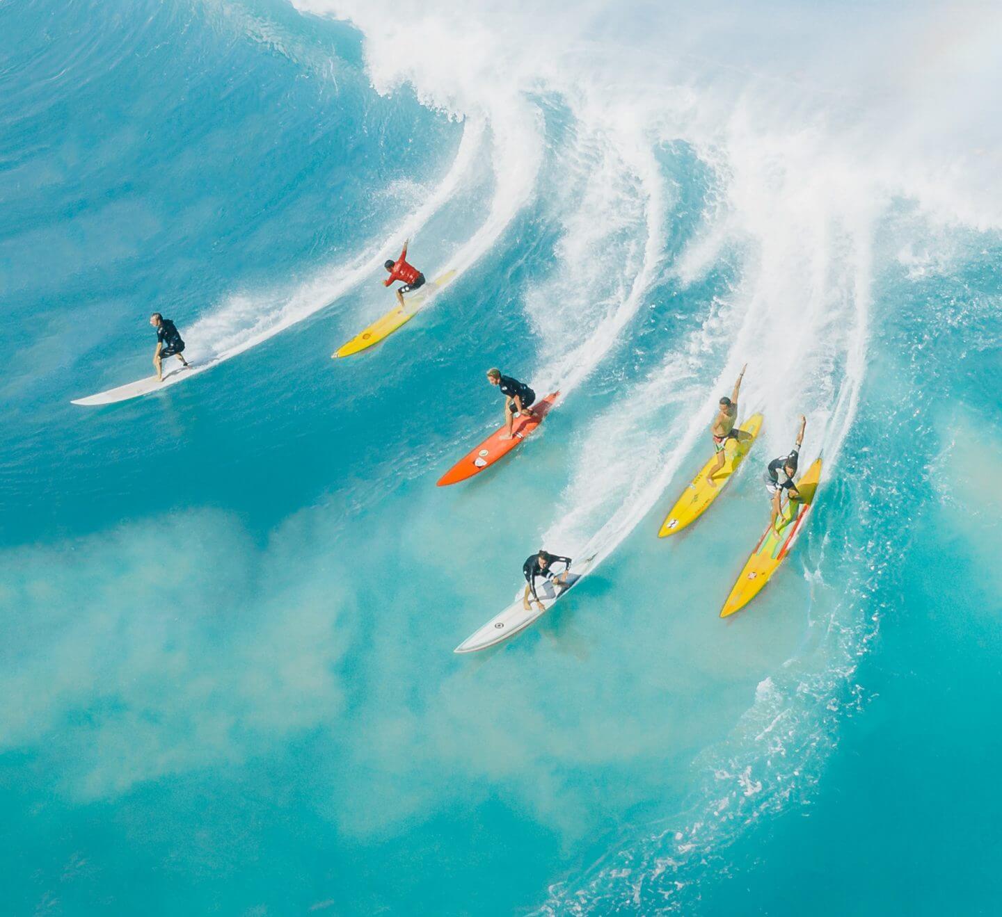 Several people surfing on a big wave