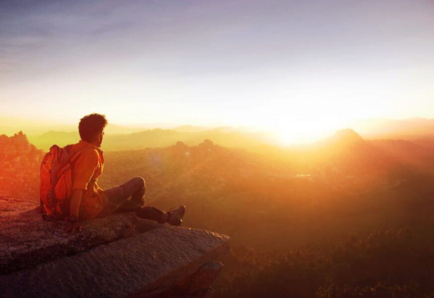 A person watching the sun rise over mountains